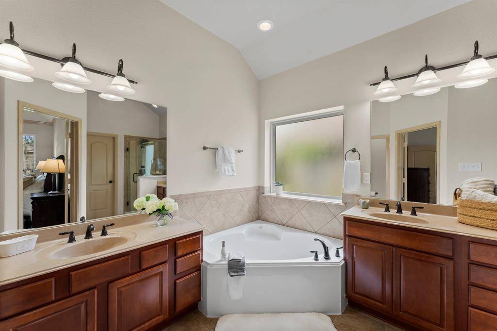 Enjoy a spa-like experience in the luxurious primary bath featuring brand new mirrors, a deep soaking tub, and dual vanities with generous counter space.