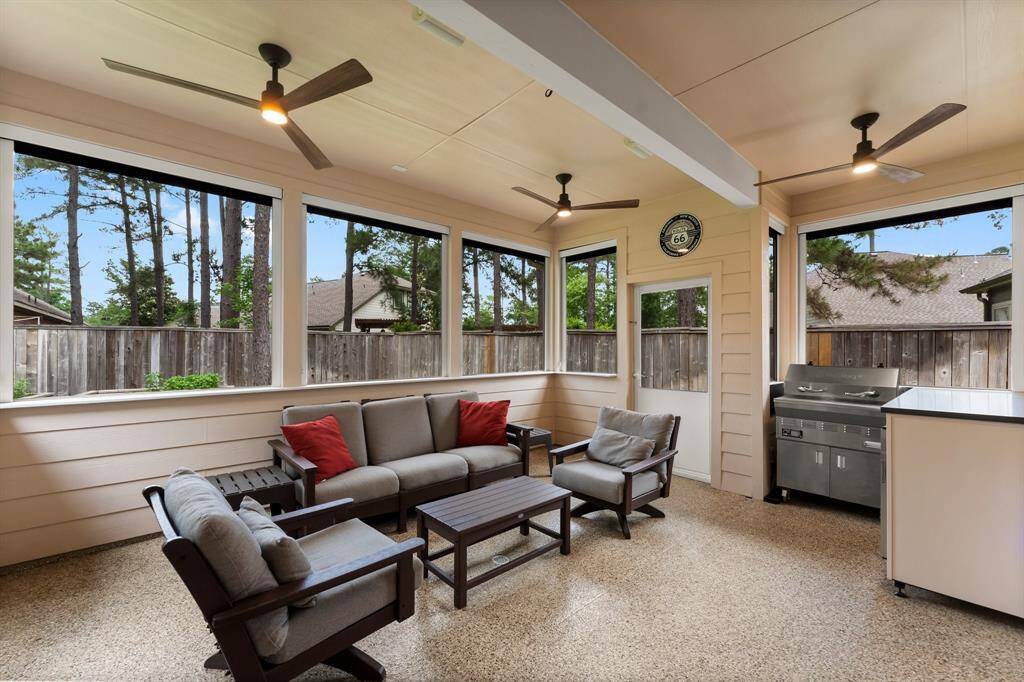 This screened-in, covered patio offers a comfortable outdoor living experience with modern ceiling fans, built-in grilling station, and sleek epoxy flooring—ideal for entertaining or relaxing year-round.