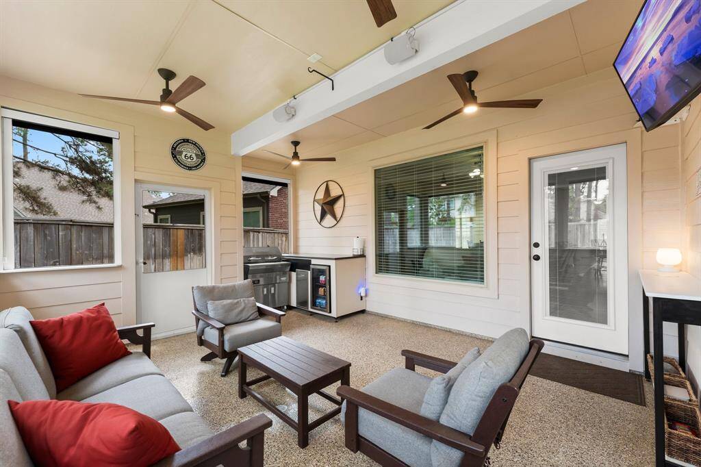 This screened-in, covered patio offers a comfortable outdoor living experience with modern ceiling fans, built-in grilling station, and sleek epoxy flooring—ideal for entertaining or relaxing year-round.
