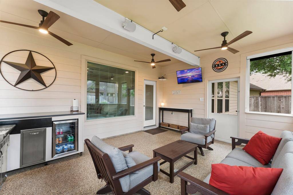 This screened-in, covered patio offers a comfortable outdoor living experience with modern ceiling fans, built-in grilling station, and sleek epoxy flooring—ideal for entertaining or relaxing year-round.
