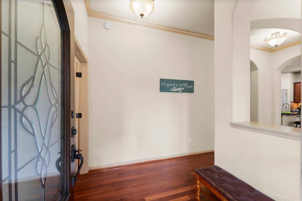 A warm welcome awaits inside, where rich hardwood floors and elegant crown molding set the tone. A beautiful glass-inset front door allows natural light to filter into the entry, creating a sophisticated first impression.