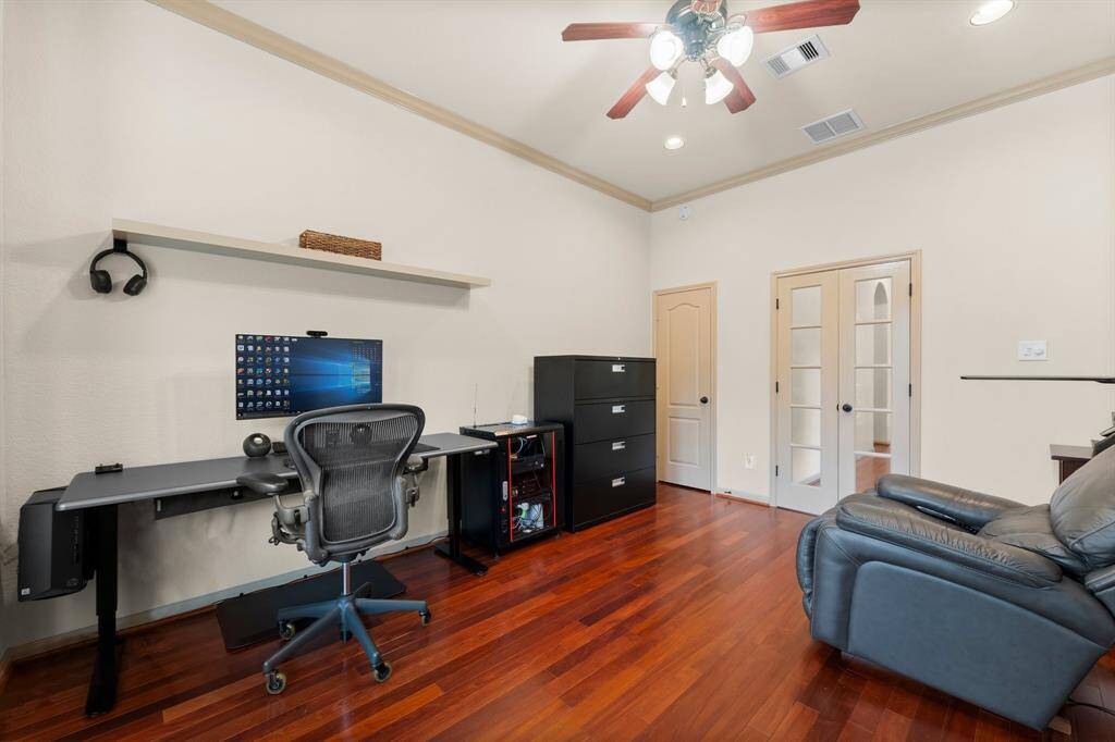 Framed by French doors and bathed in natural light from the front-facing bay window, this flexible space is currently used as a home office. Rich hardwood floors, crown molding, and recessed lighting add polish, making it an inspiring environment for productivity or relaxation.
