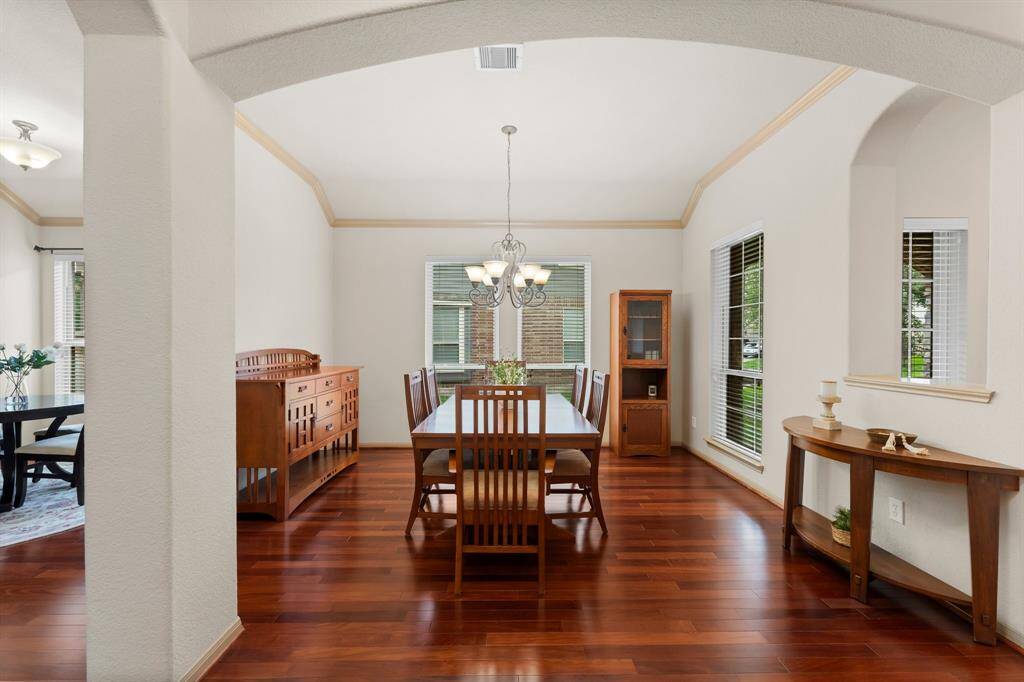 The elegant formal dining room is defined by graceful archways and enhanced by tall windows that fill the space with natural light. Hardwood flooring continues here, complemented by high ceilings and classic trim work—an inviting setting for gatherings both intimate and grand.