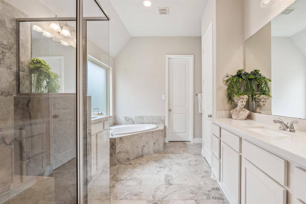 The luxurious primary ensuite offers a dual vanity, a relaxing soaking tub, and a separate glass-enclosed shower for a spa-like experience. Thoughtfully designed, it combines style and function for a serene daily retreat.