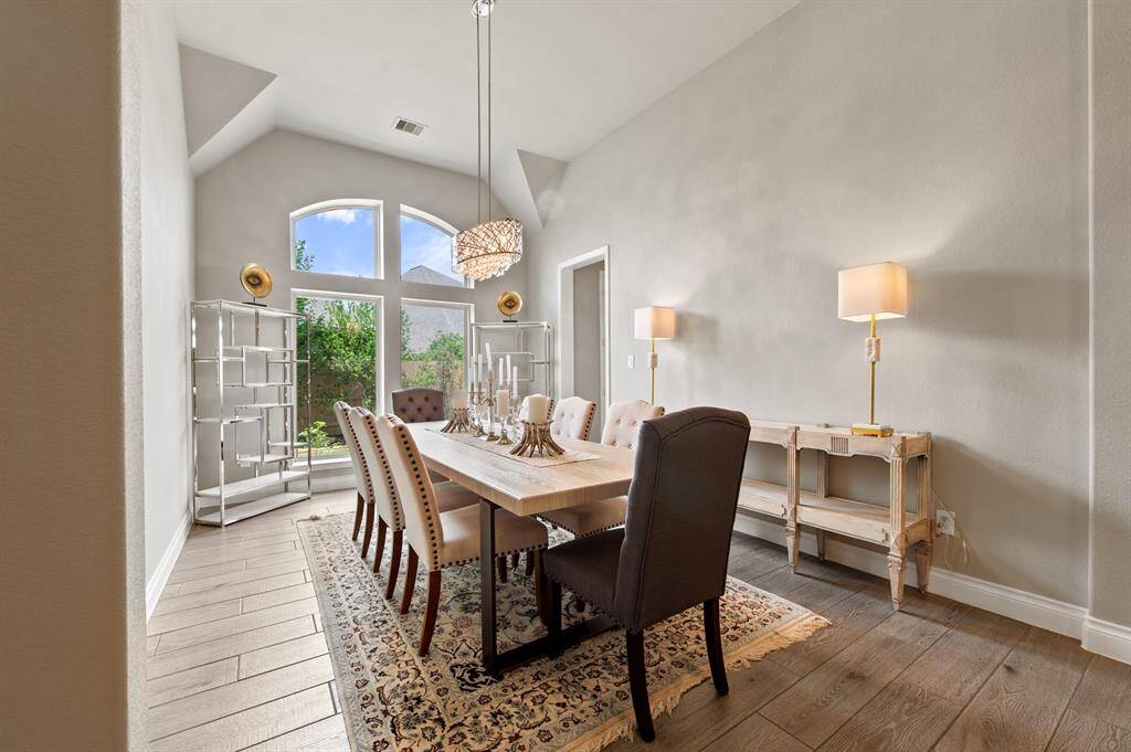 Step into an elegant dining room featuring soaring high ceilings, expansive windows that flood the space with natural light, and a stunning chandelier that adds a touch of timeless sophistication.