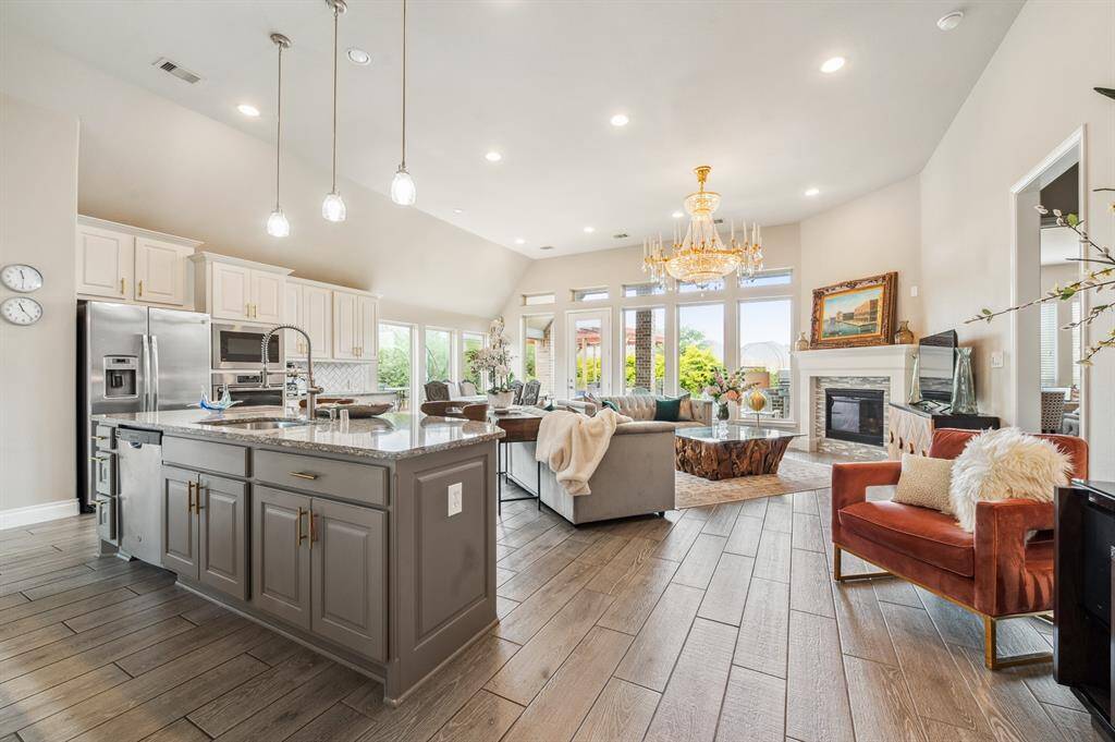 This open-concept kitchen and family room boasts large windows, an inviting island, with elegant lighting creating a warm ambiance. Perfect for both everyday living and entertaining.