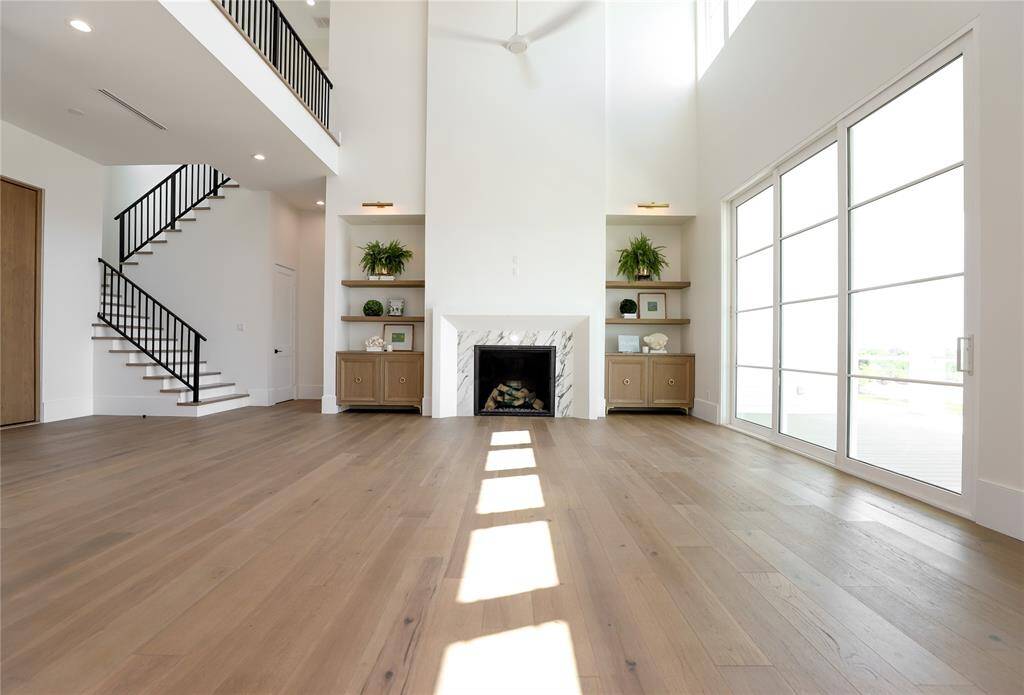 Experience modern living in this spacious room with high ceilings, a sleek fireplace, and abundant natural light. Enjoy bay breezes through large sliding doors, while built-in shelves and a stylish staircase enhance the contemporary feel.