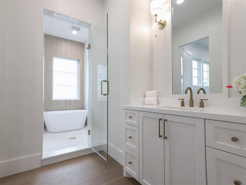 This second floor bathroom features a modern design with a freestanding tub, glass shower enclosure, and dual-sink vanity. It has sleek fixtures, ample storage, and bright lighting, creating a clean and inviting space.
