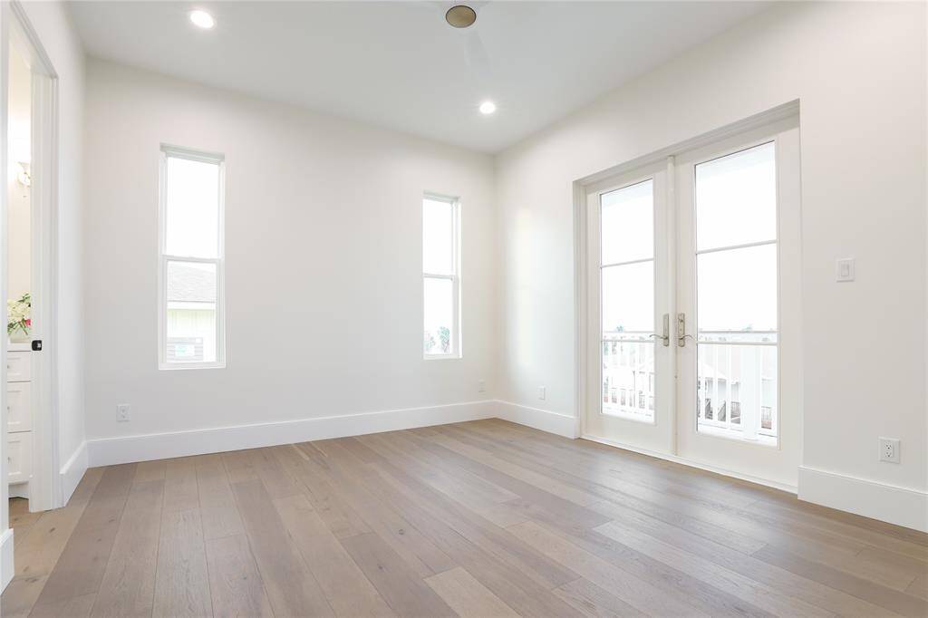 Bright, airy second floor bedroom with hardwood floors, two narrow windows, and French doors leading to a balcony.  Has 2 built in closets.