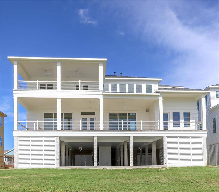 This modern three-story home features a sleek, white exterior with expansive balconies on each level. It offers ample natural light and picturesque views, perfect for enjoying outdoor waterfront living.