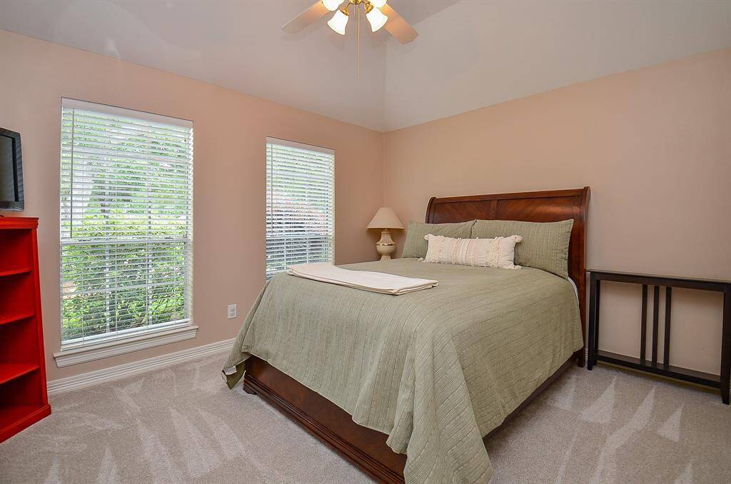 Great big windows bring pure natural light into a generous carpeted secondary bedroom.
