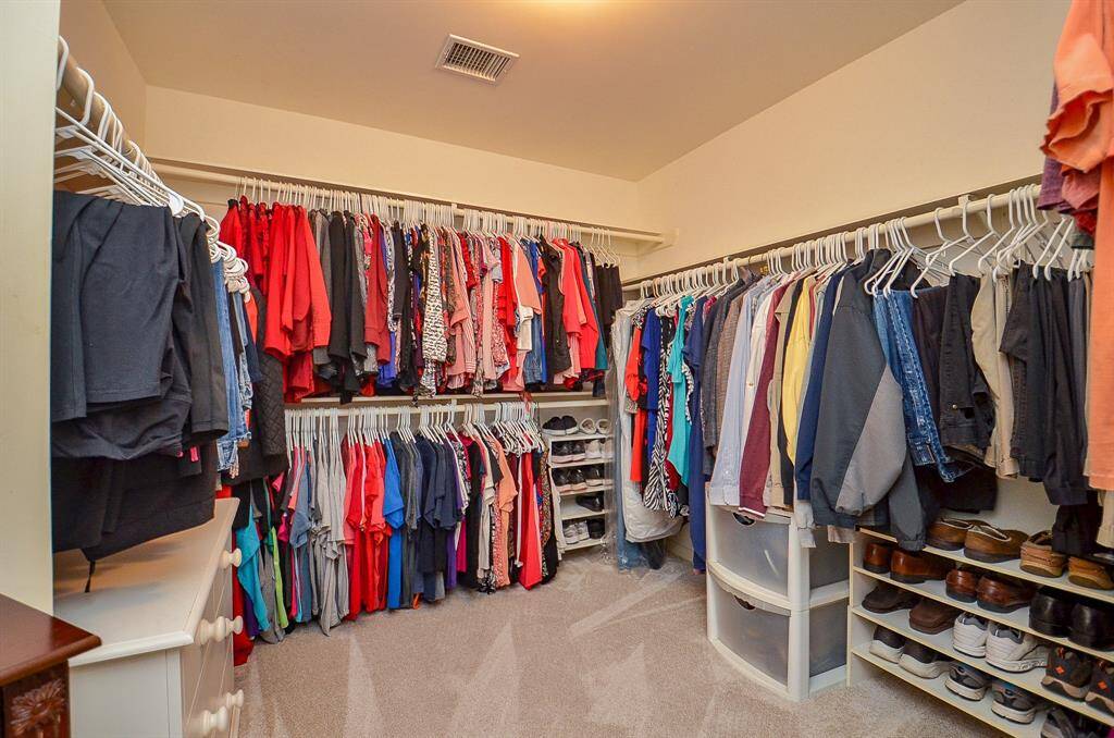 This incredible carpeted primary walk-in closet stores and organizes just about everything you own, in one space!