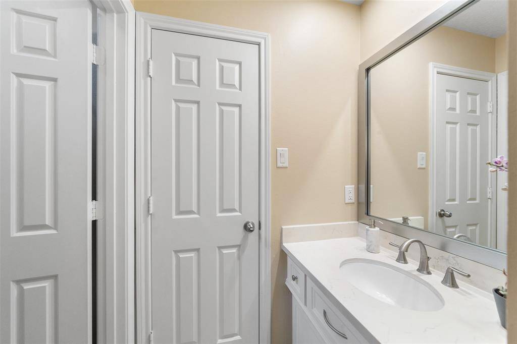 This is a modern bathroom featuring a sleek vanity with a white countertop and an undermount sink.