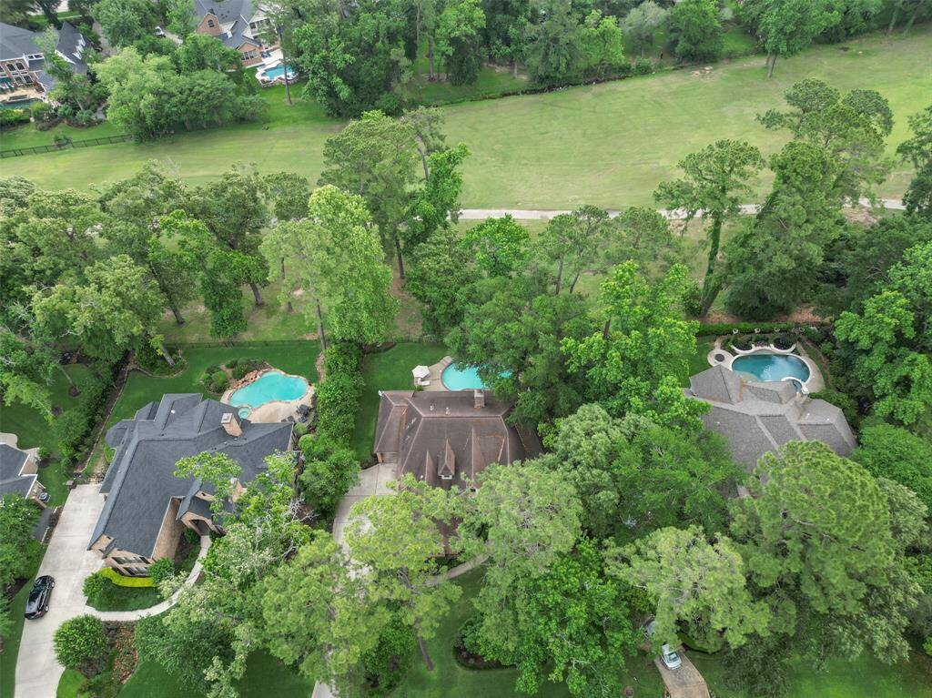 This aerial photo showcases a beautiful, golf course with spacious homes featuring large yards and private swimming pools. The area is surrounded by mature trees, providing privacy and a serene atmosphere.