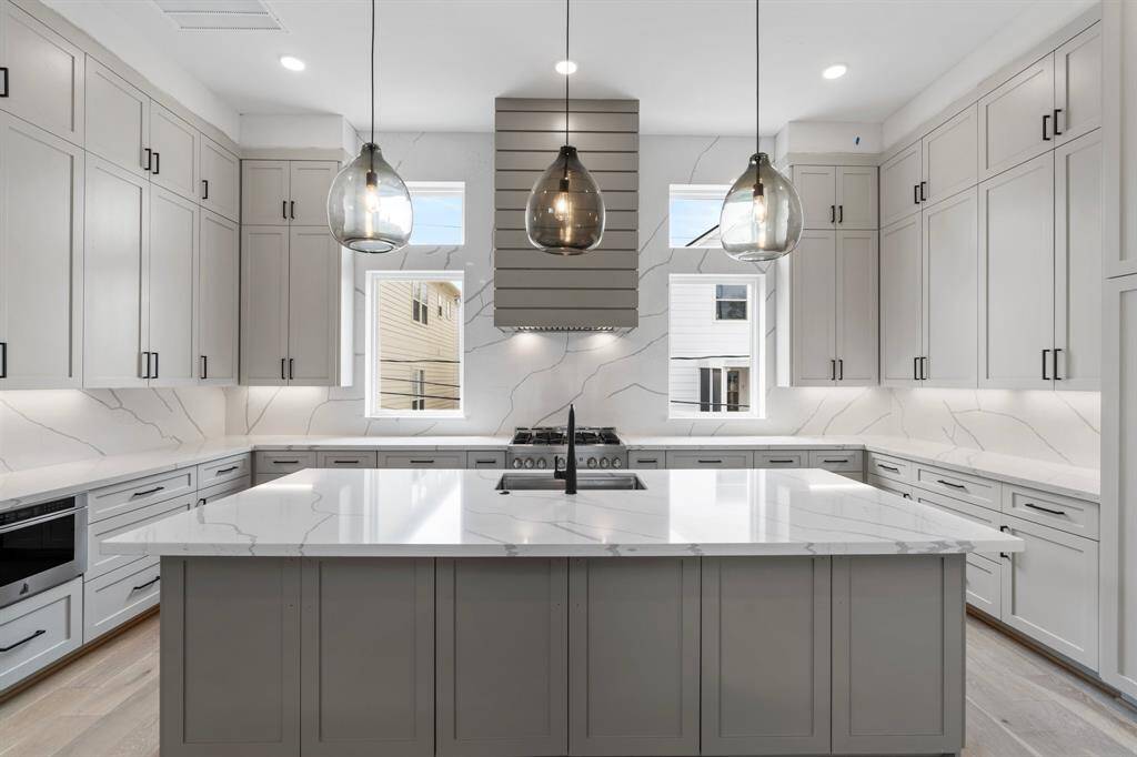A chef’s dream kitchen, perfectly located on the 2nd floor for easy entertaining w/ the main living spaces! Featuring stunning quartz countertops, a custom vent hood & a full quartz backsplash. Expansive island w/ breakfast bar seating features 3 Visual Comfort Pendant lights above.