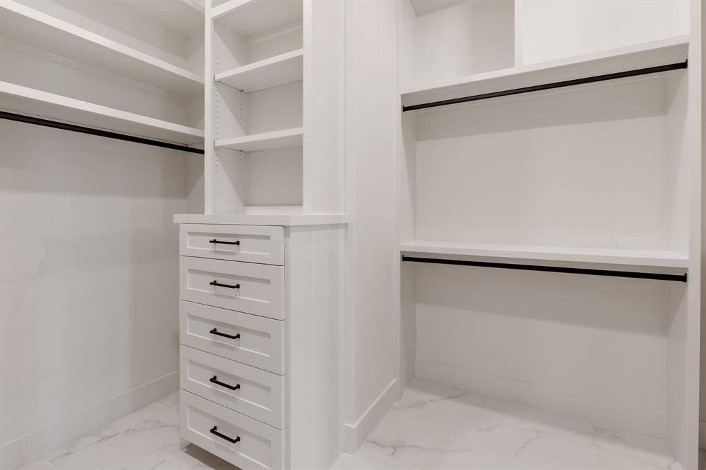 A peek into the large walk-in closet with his and hers dressers and hidden storage.