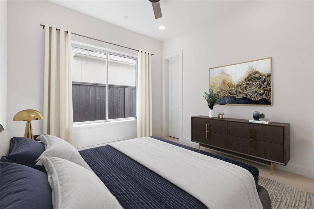 This spacious secondary bedroom #2 on the first floor offers a Visual Comfort ceiling fan, large window, and recessed can lighting. With an electrical outlet for a future TV and a generous walk-in closet with built-in dresser, it’s designed for both comfort and convenience. Note: this photo has been virtually staged.