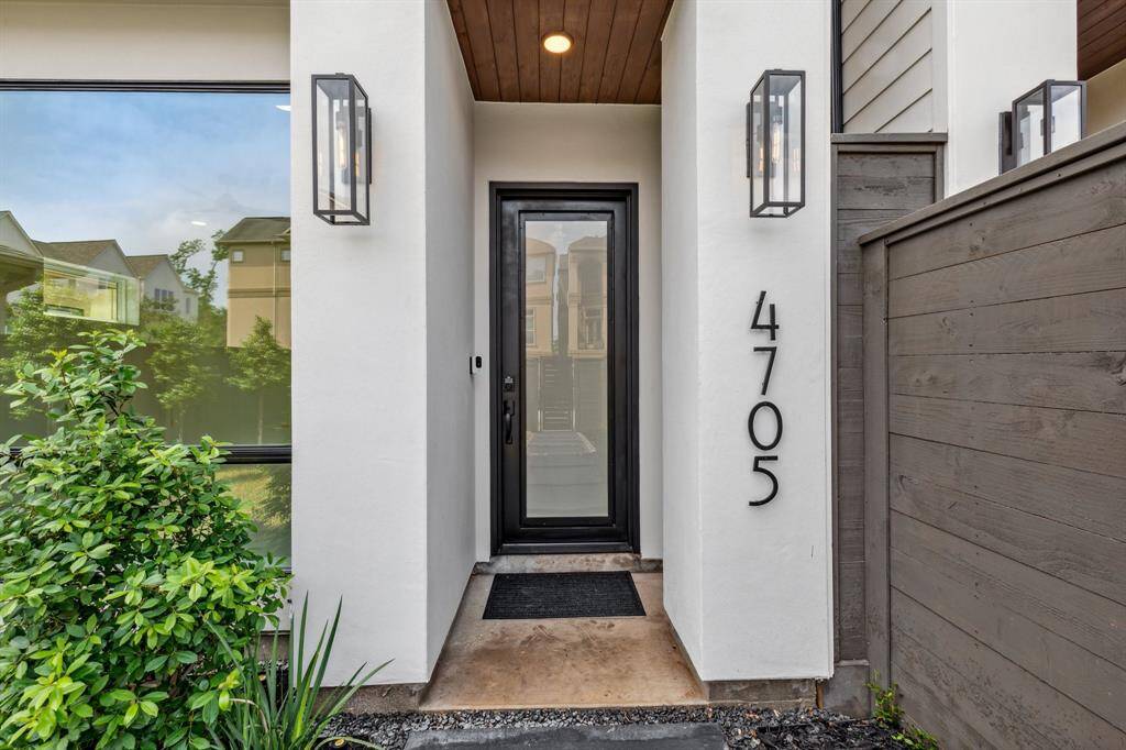 Welcome home through a striking custom steel front door, flanked by designer Visual Comfort exterior lights and a smart security doorbell for added peace of mind and style.