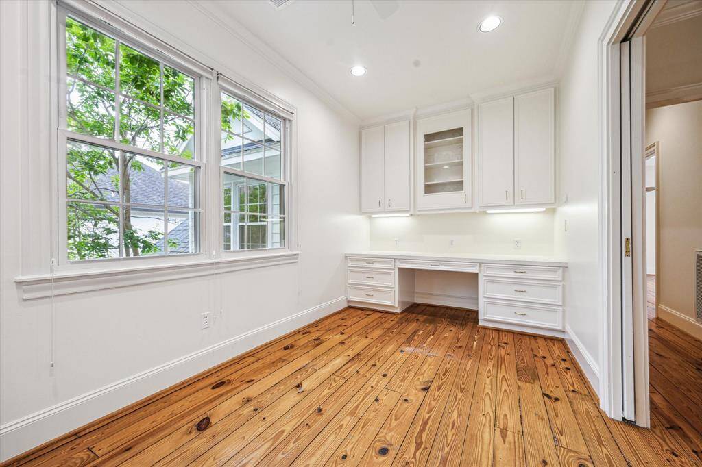 This upstairs office space features built-in cabinetry, a generous work surface, and serene views framed by large windows that invite natural light throughout the day.