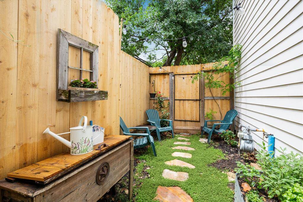 This charming side garden offers a cozy retreat with string lights, Adirondack chairs, and a whimsical wall planter that adds rustic character. A stepping stone path winds through lush greenery, creating the perfect nook for relaxing or tending to your favorite plants.