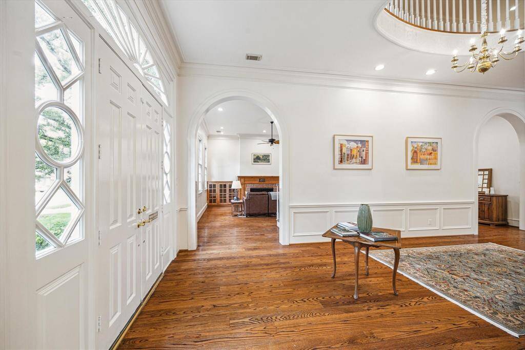 This additional view of the entry reveals elegant archways, intricate millwork, and seamless flow into the sunlit living spaces beyond.