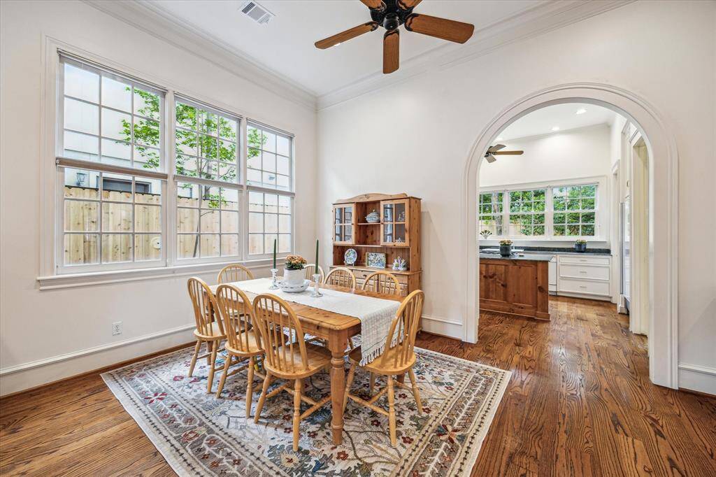 Framed by expansive windows and an elegant arched entry, this charming breakfast room is filled with natural light and offers a seamless connection to the bright, spacious kitchen beyond.