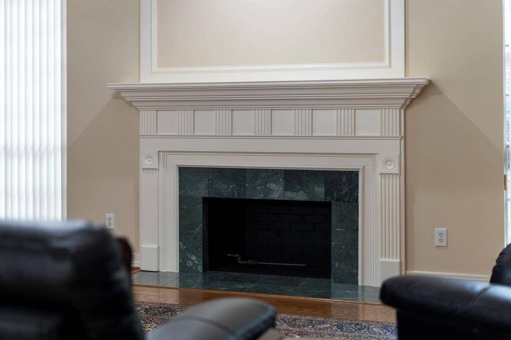 A classically designed fireplace with elegant marble tile serves as the striking focal point in the family room.