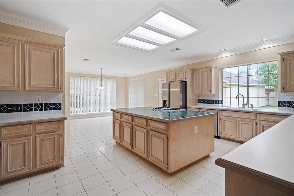 The heart of the home is a sprawling kitchen and breakfast area, featuring a large center island with gas cooktop, double wall ovens, and a walk-in pantry—perfect for culinary creativity and family gatherings.