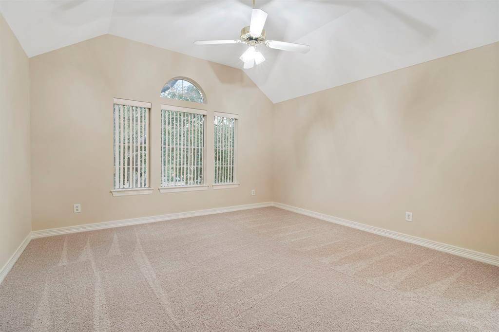 This spacious secondary bedroom is highlighted by a vaulted ceiling and a stunning Palladian window, allowing natural light to fill the room while adding an elegant architectural touch.