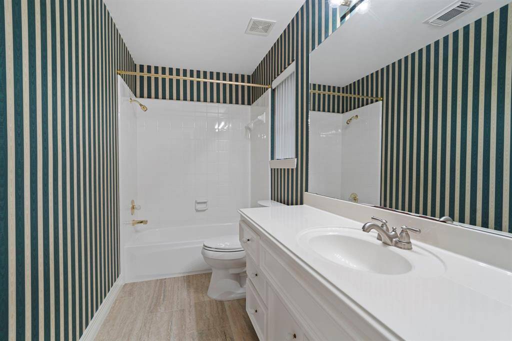 The en suite bathroom is thoughtfully designed with a shower/tub combination, a spacious vanity, and updated Italian tile flooring that adds a fresh, modern touch.