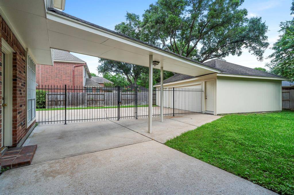 A covered breezeway connects the home to the detached three-car garage, offering protection from the elements and a shaded space perfect for seating or outdoor grilling.