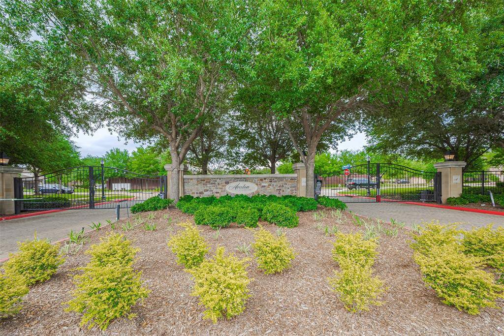 This photo shows an inviting entrance to a gated community, featuring lush greenery, well-maintained landscaping, and a secure metal gate, offering privacy and exclusivity.