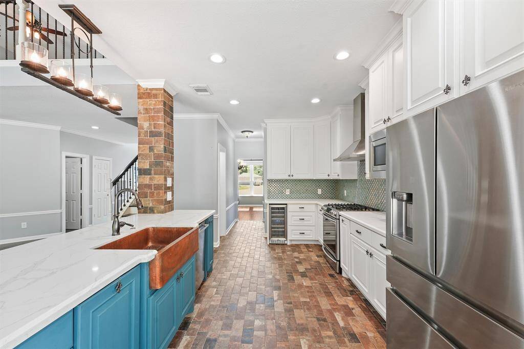 Kitchen area with quartz countertops, stainless steel appliances and copper sink.
