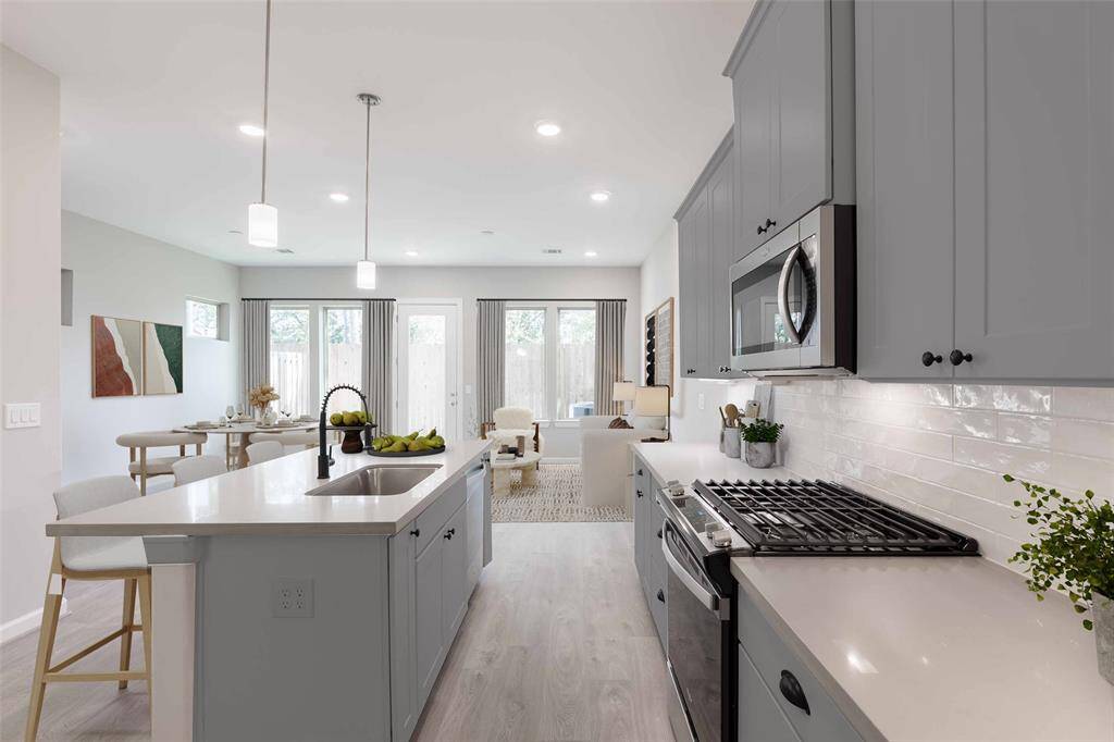 Beautifully equipped kitchen with seating isalnd open to living and dining. (virtually staged)