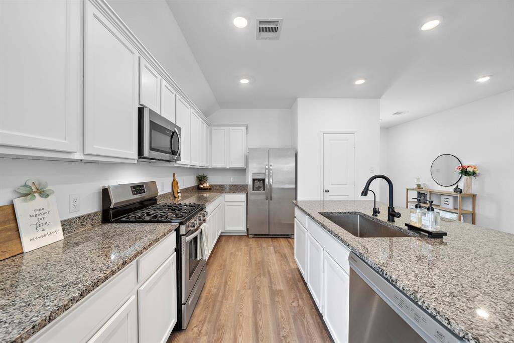 The modern kitchen features sleek granite countertops, stainless steel appliances, and ample white cabinetry. Enjoy this warm and inviting space, perfect for cooking and entertaining.