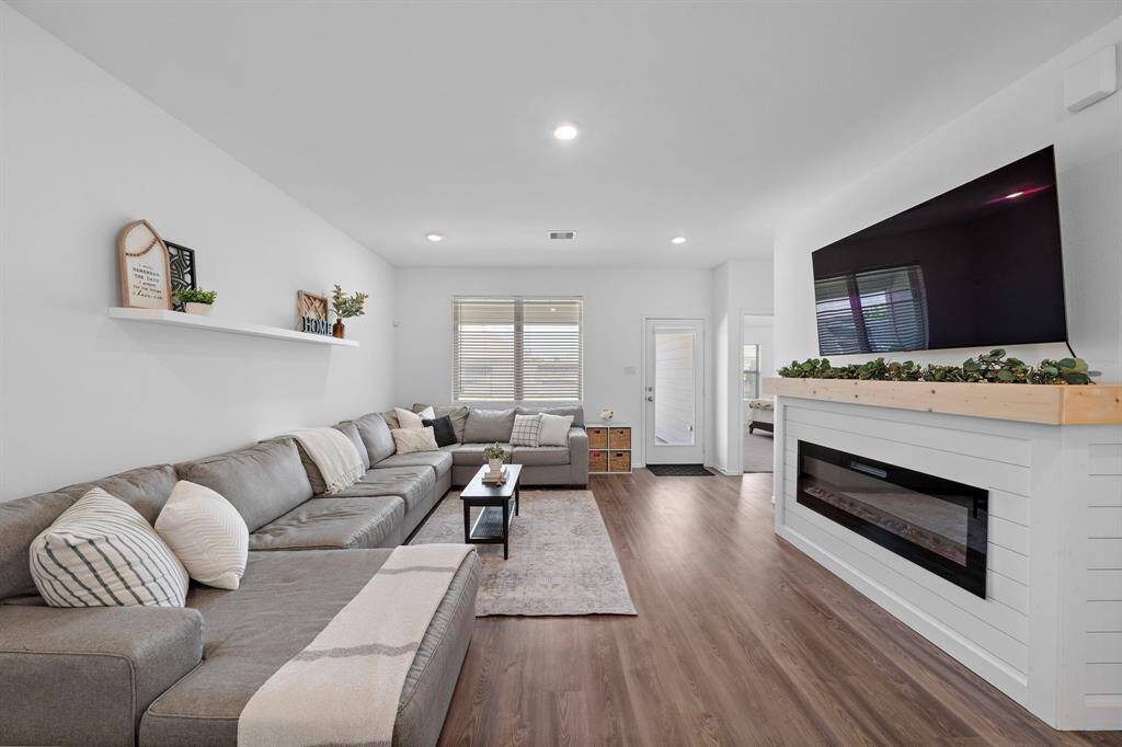 The living room is bright, thanks to the natural light from the windows, and the wood-like flooring adds warmth.