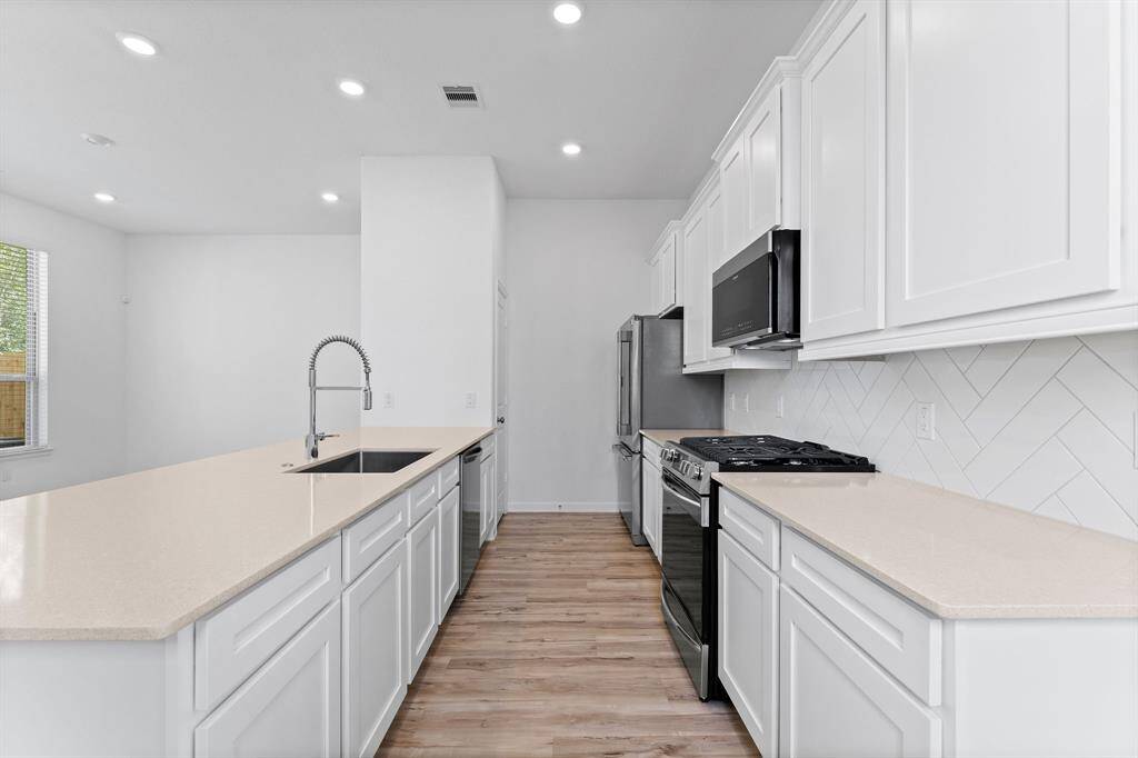 A pristine view of what this extraordinary kitchen has to offer.  Stainless steel appliances include 5 burner cooktop, convection oven, dishwasher, refrigerator, and convection microwave. This elegant kitchen boasts plenty of rich cabinets and sleek quartz counter top workspace.