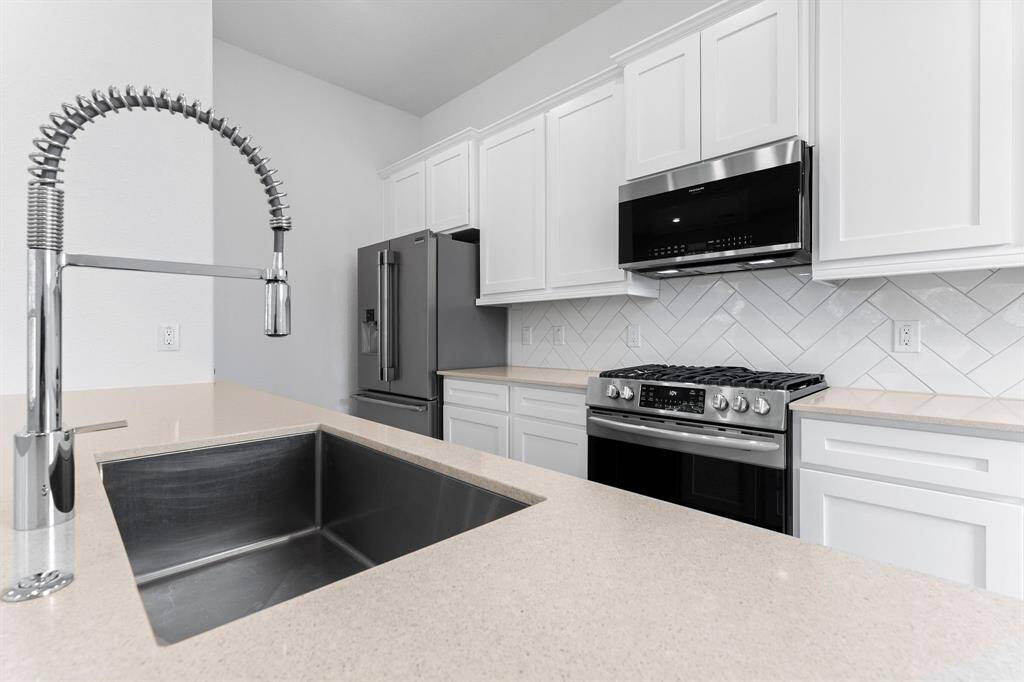 The cool clean lines in the kitchen are sure to impress! The herringbone tile backsplash and under-cabinet lighting provide class and functionality, and the large pantry holds all your appliances and cooking supplies. The single bowl stainless sink with industrial-style sprayer makes clean up a breeze!