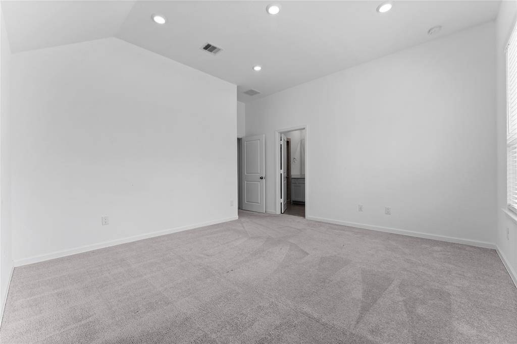 The sophisticated owner’s suite offers a peaceful retreat, designed for comfort and style. Featuring plush carpeting, recessed lighting, a graceful sloped ceiling, and a private en-suite bath, this spacious haven is perfect for your coziest furnishings—a place to relax, recharge, and escape the everyday.