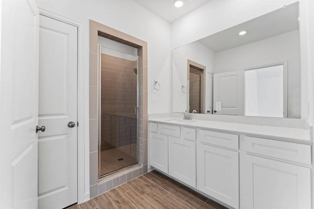 The owner’s sink area showcases a gleaming quartz counter top with extended vanity area to allow ample room for pampering. The large rectangular-tiled shower with built-in toiletry shelves and large rainfall shower-head is perfect for an invigorating wake-up in the morning.