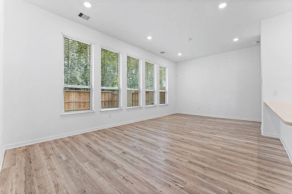 This home offers a spacious, open-concept layout where the living and dining areas seamlessly flow into the kitchen—perfect for modern living. Enjoy breathtaking views of the wooded backdrop through five large windows, all outfitted with blinds for privacy. The living space is enhanced by wood-look laminate flooring, rounded wall corners, and recessed lighting, creating a warm and inviting atmosphere.