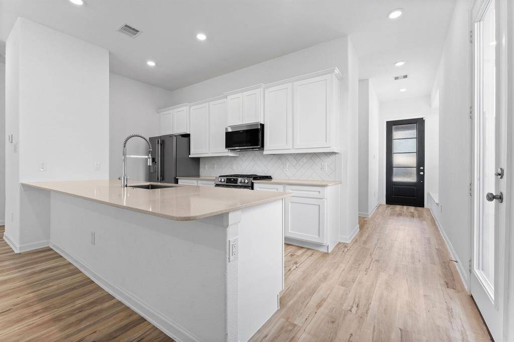 A dream for any gourmet chef, this generously sized kitchen offers both style and function. Highlights include a spacious peninsula with ample storage and prep space, sleek recessed lighting, striking exotic quartz countertops, and warm wood-look laminate flooring that ties it all together beautifully.