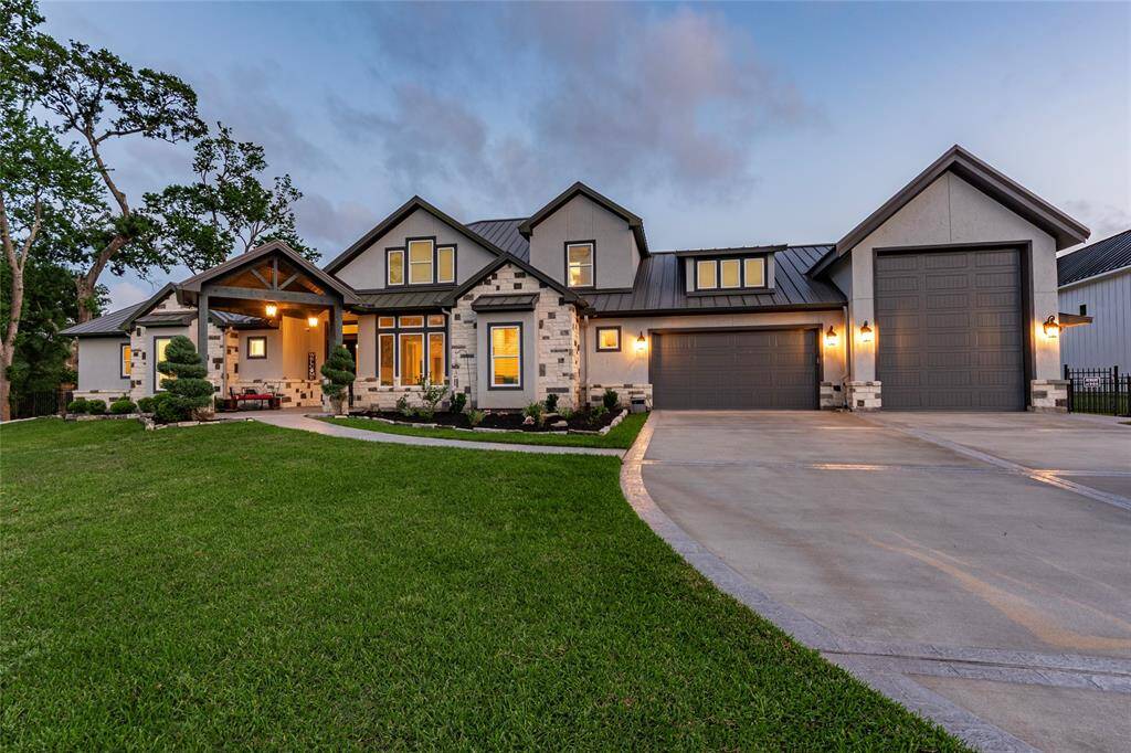 Twilight unveils the grandeur of this 5,500+ sq ft estate, showcasing 3,608 sq ft of elegant living space and a massive 2,000 sq ft garage with RV doors—all under a striking metal roof.