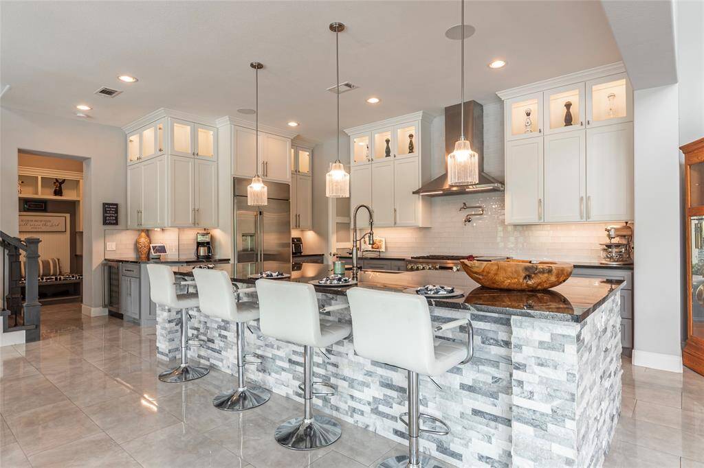 Striking custom island kitchen featuring custom cabinets with accent lighting and a remarkable 13-foot granite island with stacked stone accents, offering both functionality and high-end design perfect for entertaining and everyday living.