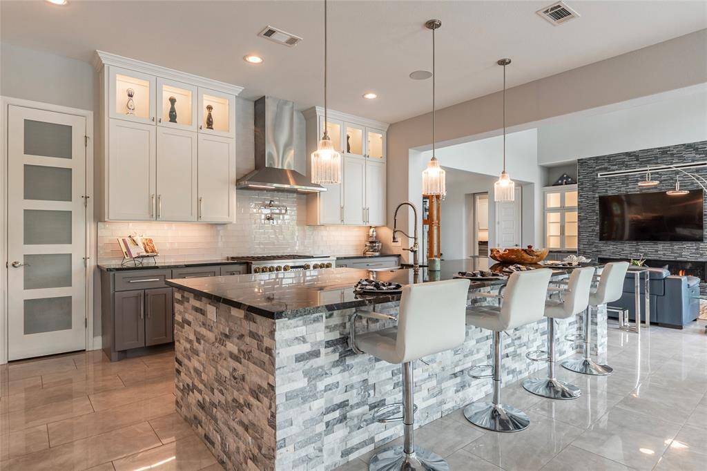 This luxury kitchen is equipped with a convenient pot filler above the professional-grade gas stove/range, complemented by soft-close cabinetry, a spacious walk-in pantry with floor-to-ceiling shelving, and sleek stainless steel appliances—crafted for both style and culinary excellence.