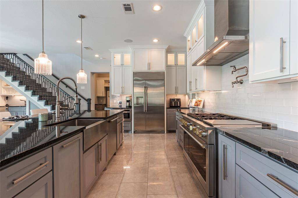 The kitchen is appointed with a stainless steel farmhouse sink and upscale faucet, modern pendant lighting, under-cabinet illumination, a built-in wine chiller, and a side-by-side stainless steel refrigerator—blending style and function in every detail.Modern kitchen features large stainless steel farmhouse sink & upscale faucet, modern pendant lighting, under-cabinet lighting, built-in wine chiller & side-by-side stainless steel refrigerator—blending style and function in every detail.