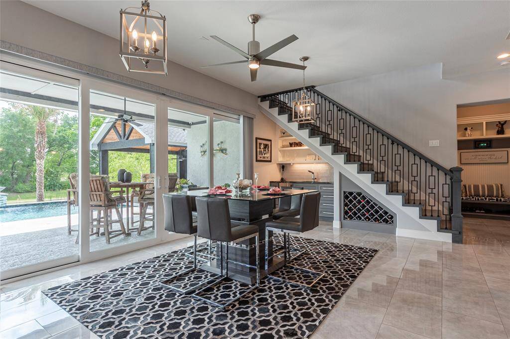 The beautifully designed dining room features a custom wet bar with built-in wine rack, a separate wine chiller, and ice maker, while storm-proof sliding glass doors provide direct access to the outdoor pool and patio—ideal for stylish indoor-outdoor entertaining.