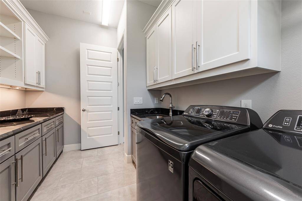 The convenient utility room, located adjacent to the wardrobe closet, is equipped with a sink, faucet, granite folding counter, storage shelves and soft-close storage cabinets—offering both practicality and style for everyday tasks.