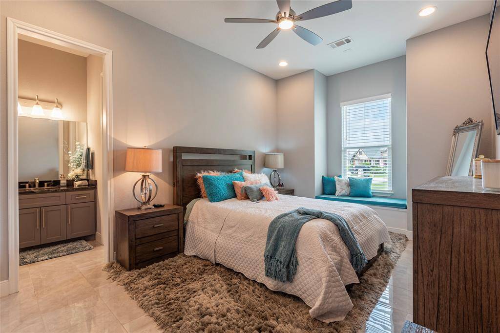 Secondary bedroom conveniently located on the first level offers tile flooring and an en-suite bathroom featuring granite countertops, a walk-in shower, and a spacious walk-in closet—providing comfort and privacy for guests or family.