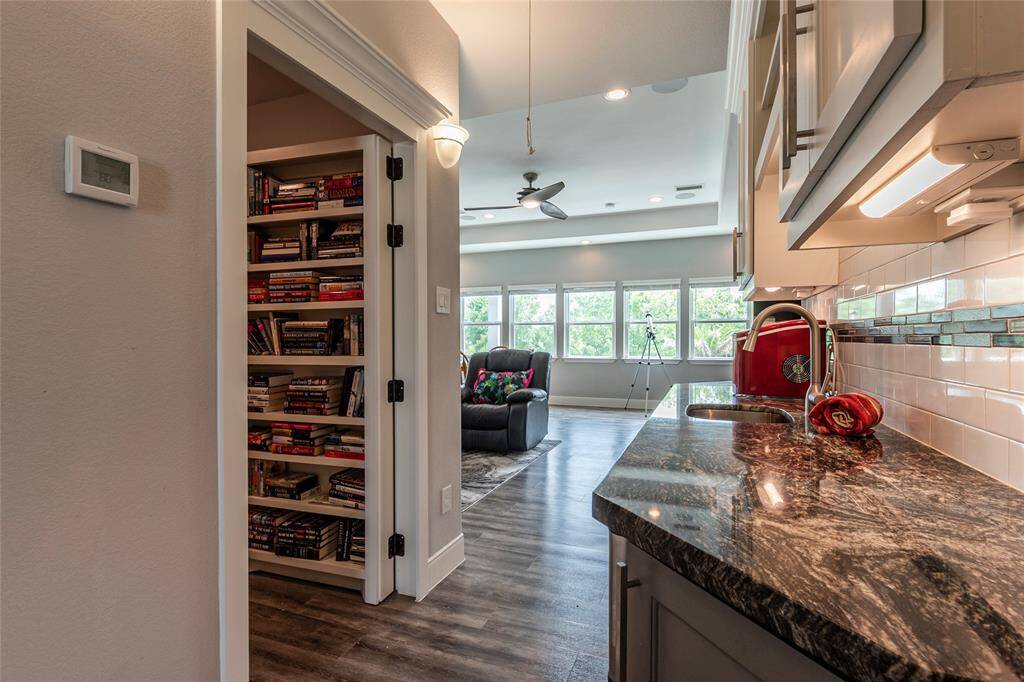 Another perspective of the upstairs layout with large game/media room located adjacent to wet bar with additional storage, granite countertops and cabinet storage with undermount lighting; the upstairs is complete with secret bonus room, bedroom, full bathroom and a decked walk-in attic—complete an automatic lift from the garage for effortless storage access.